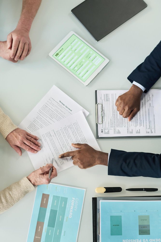 Hands over printed documents on a table during a contract discussion